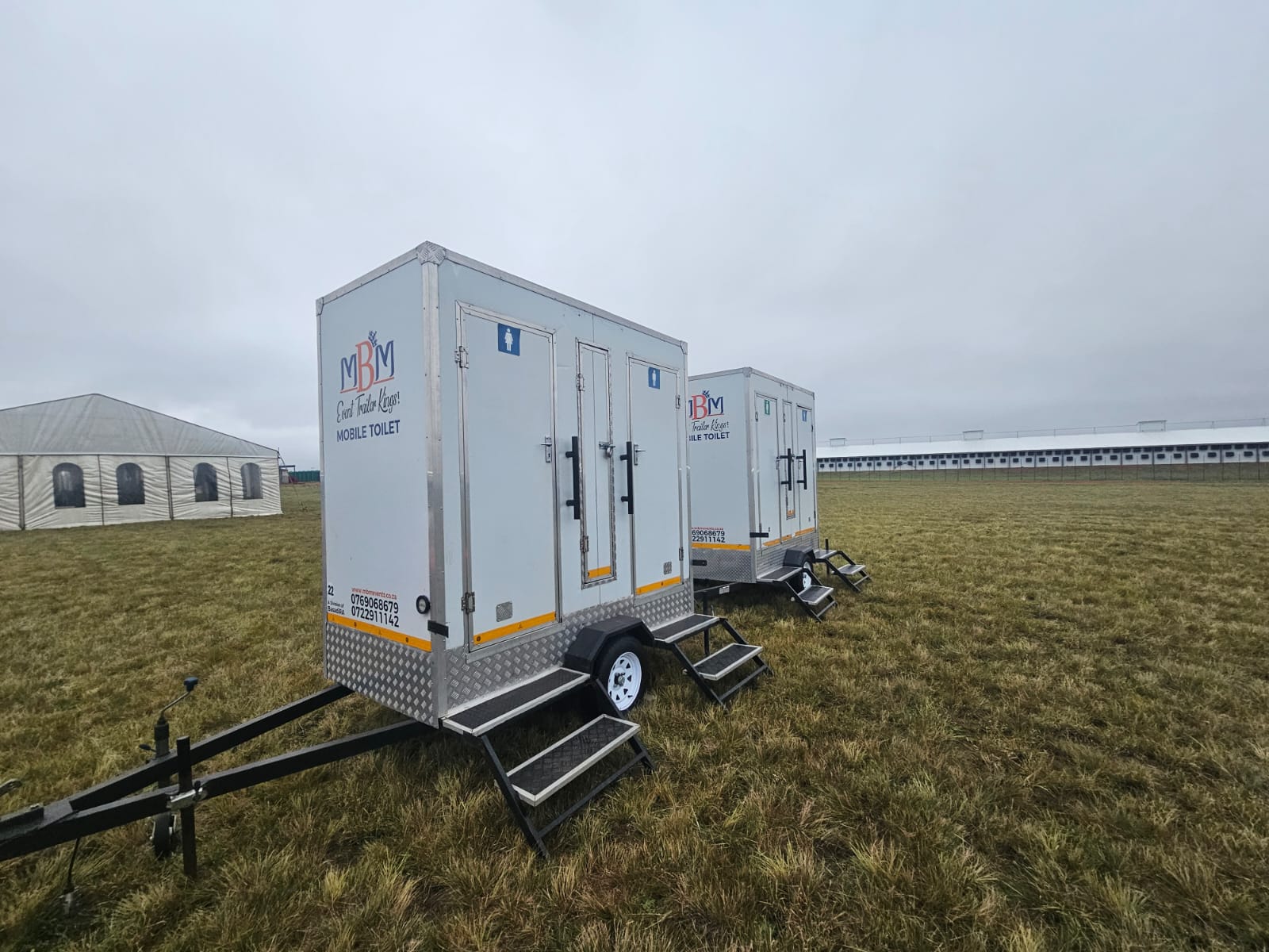 MBM mobile toilet trailers beside an event marquee